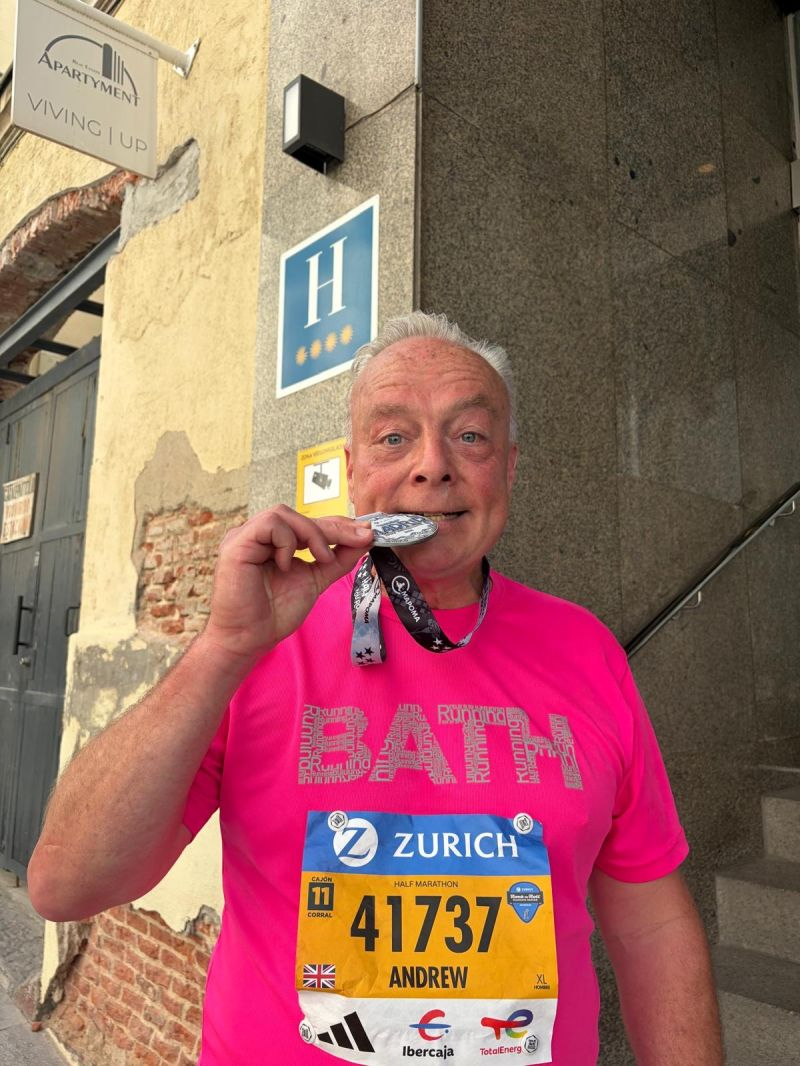 Man biting a medal while wearing a marathon bib